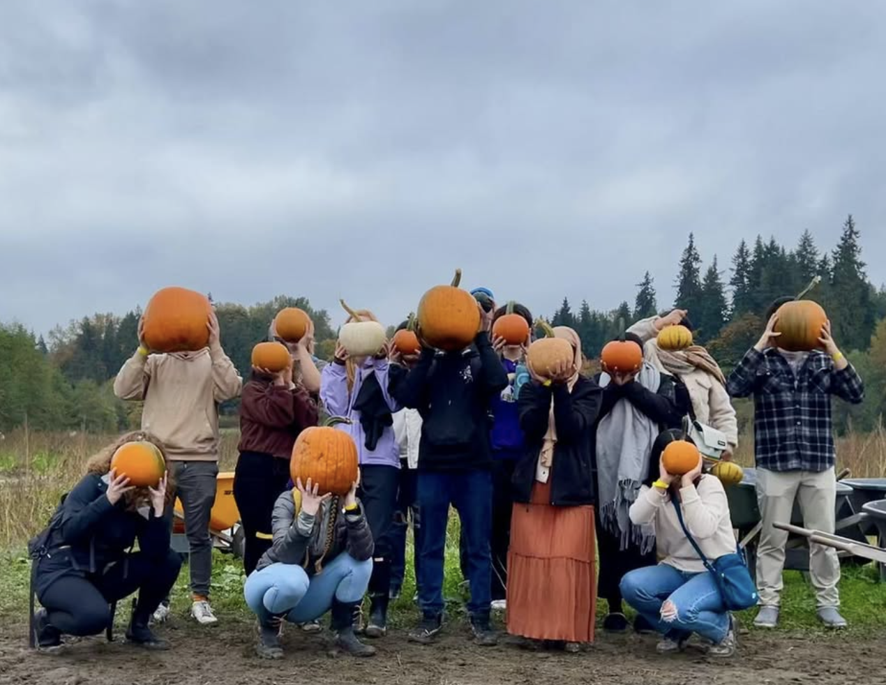 Passport to Change students gathering together outdoors, holding pumpkins to maintain privacy